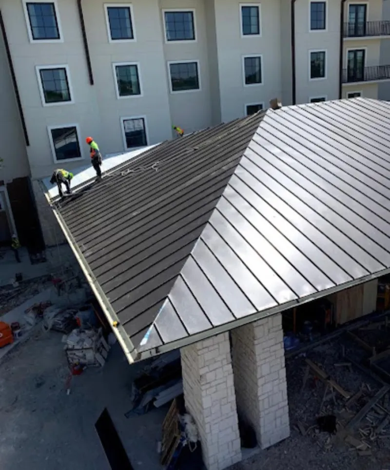 Crew installing standing seam metal roof panels on a commercial project in Lynwood